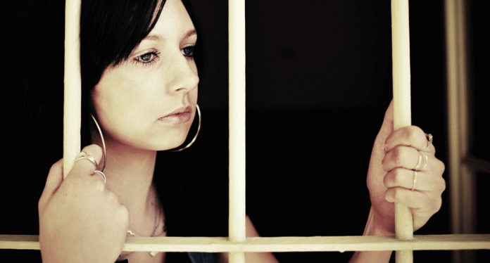 Young-woman-looking-from-behind-the-bars-800x430